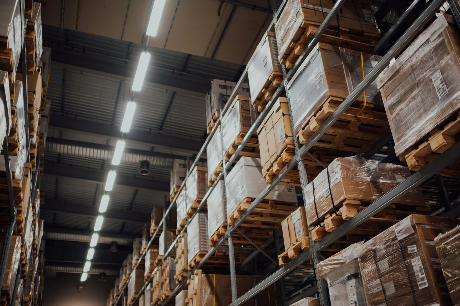 Interior of a large warehouse with tall storage racks filled with pallets and packaged goods, showcasing organized inventory and logistics storage operations.
